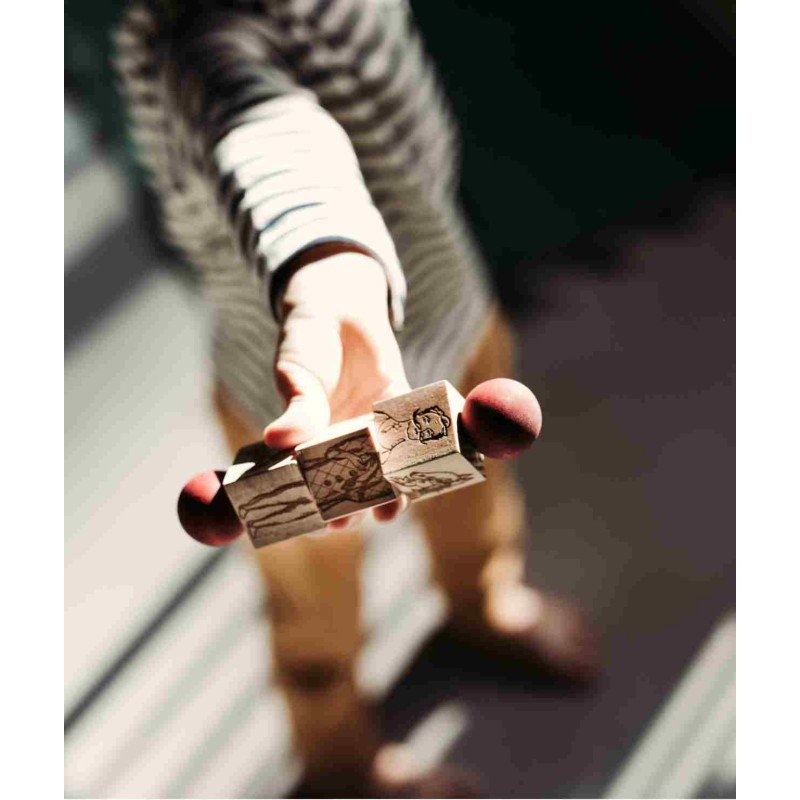 3. Close-up of child holding wooden spinning puzzle with red ends, focus on engraved details
