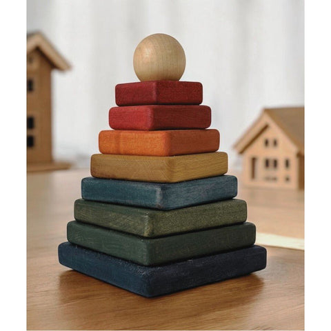 1. Wooden square pyramid toy with colorful blocks and natural ball on top, placed on wooden table with toy houses in background