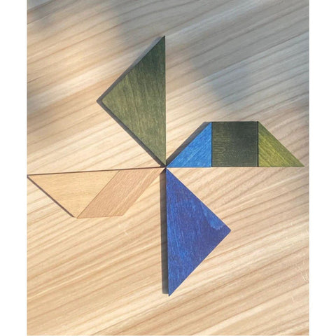 3. Wooden Story tangram pieces in cold colors arranged in a windmill shape on a wooden surface