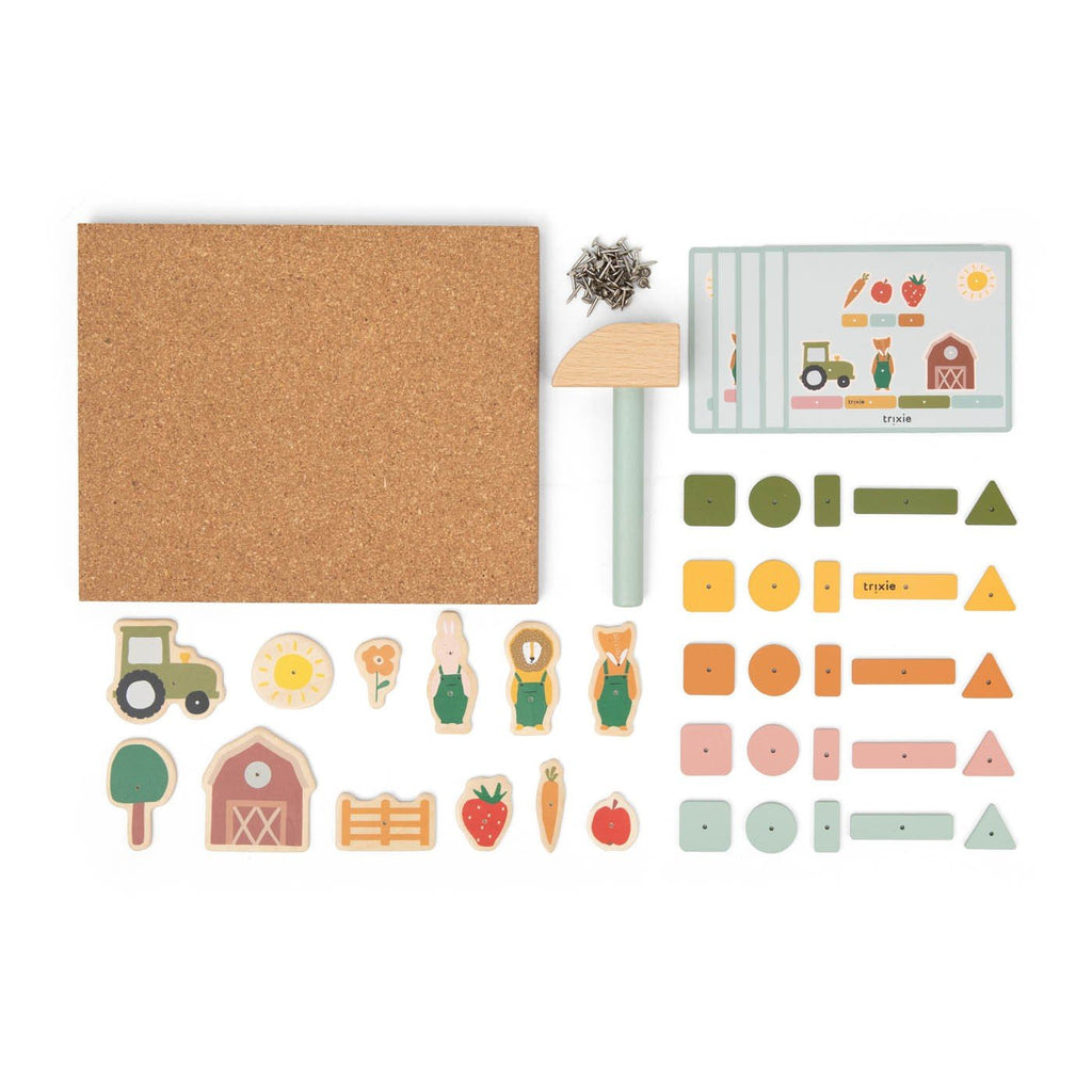 4. Flat lay of Trixie Baby wooden tap tap game components including cork board, hammer, farmyard pieces, and playing cards