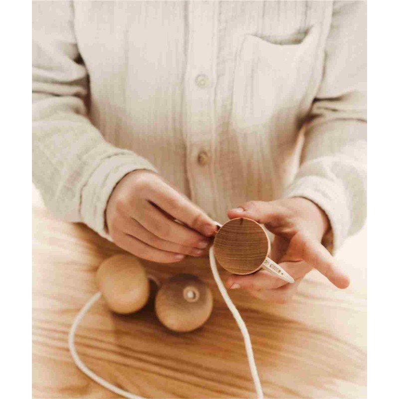 1. Child threading wooden ball with Wooden Story needle on a table