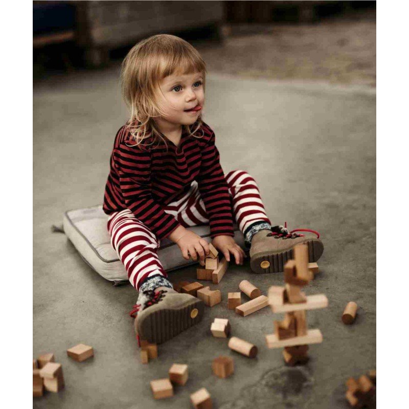 1. Child sitting on cushion playing with wooden blocks on the floor, wearing striped outfit