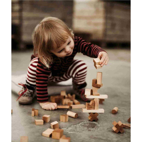 1. Child in striped outfit stacking Wooden Story natural wooden tower puzzle blocks on the floor