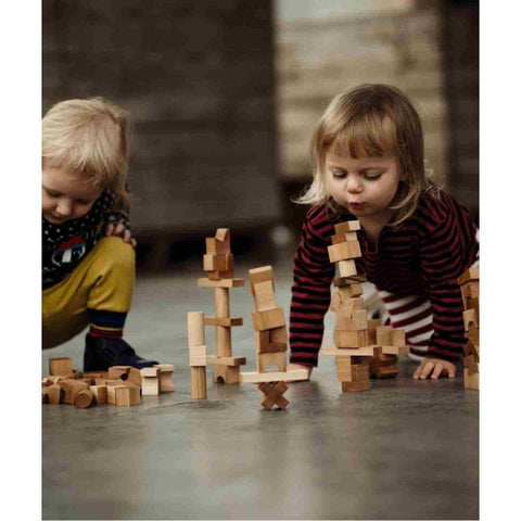 1. Two children playing with Wooden Story natural wooden tower puzzle blocks on a concrete floor