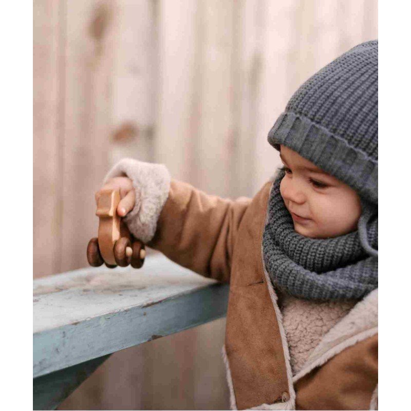 1. Child in winter clothing playing with Wooden Story duck toy on a wooden bench
