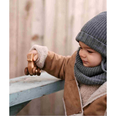 1. Child in winter clothing playing with Wooden Story duck toy on a wooden bench