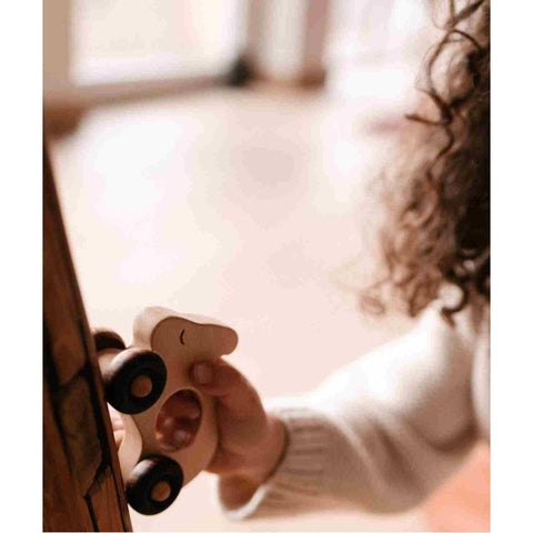 1. Wooden rabbit toy on wheels next to packaging, placed on wooden surface outdoors
