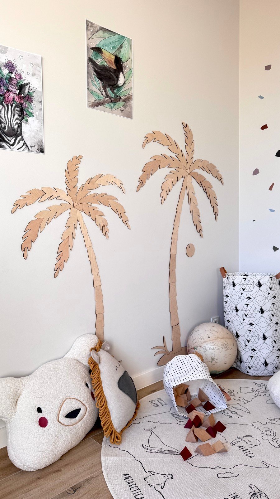 6. Children's room with two wooden palm tree wall decors, natural plywood, surrounded by plush toys and a play mat, creating a tropical theme