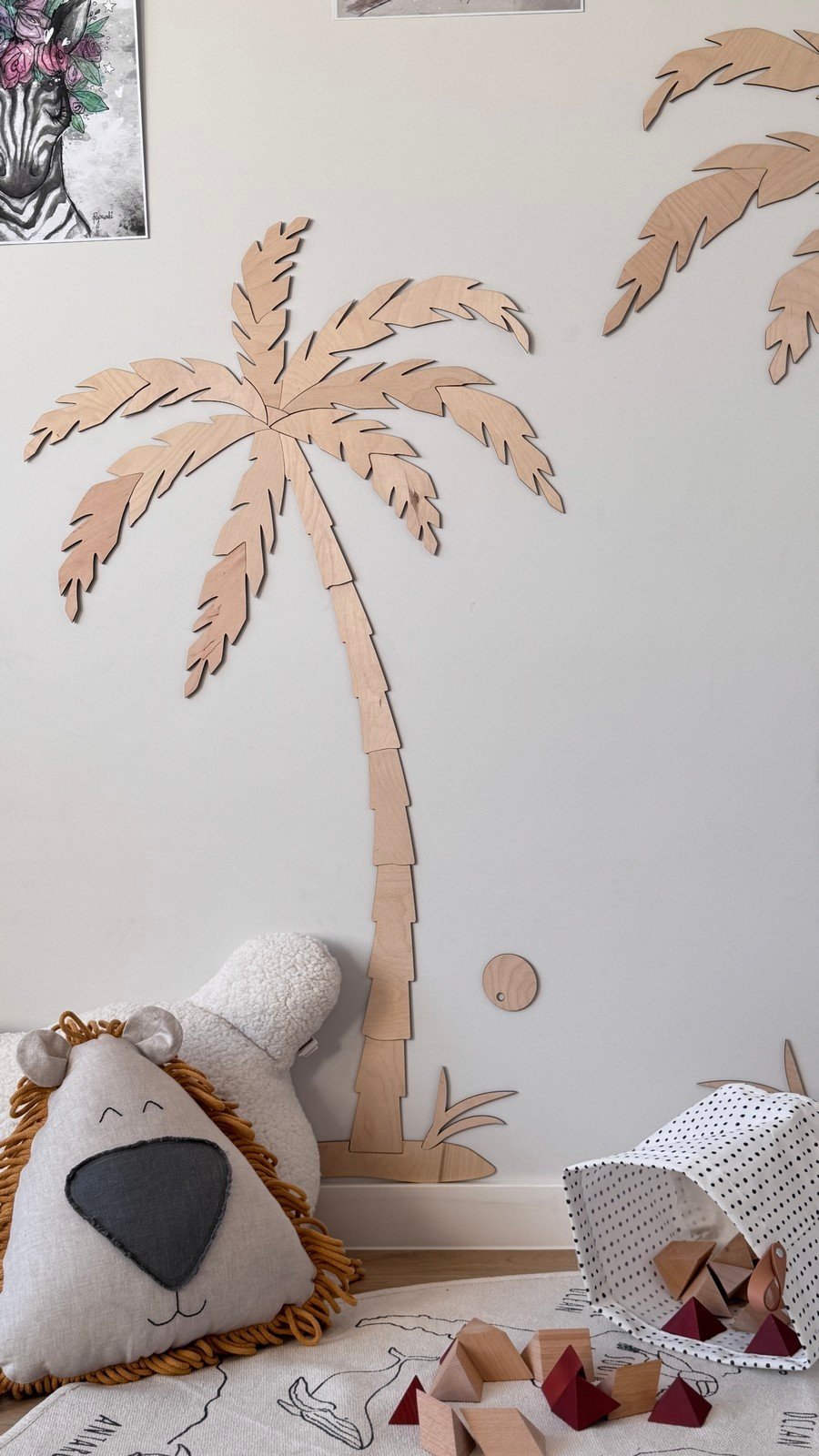 7. Close-up of small wooden palm tree wall decor in children's room, natural plywood, with plush toys and a play mat