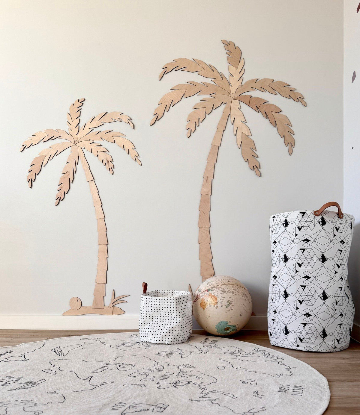 2. Minimalist children's room featuring two wooden palm tree wall decors made from natural plywood, with a globe and storage baskets on the floor
