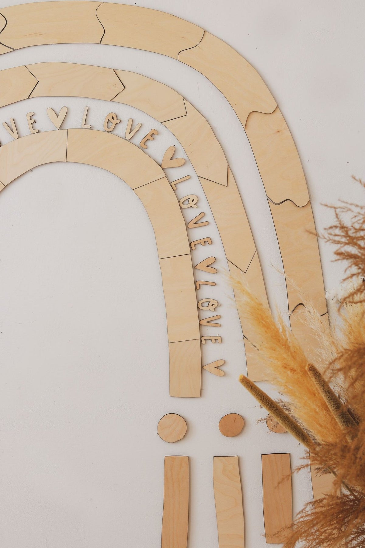 4. Close-up of wooden rainbow puzzle pieces with the word 'LOVE' engraved, showing detailed craftsmanship