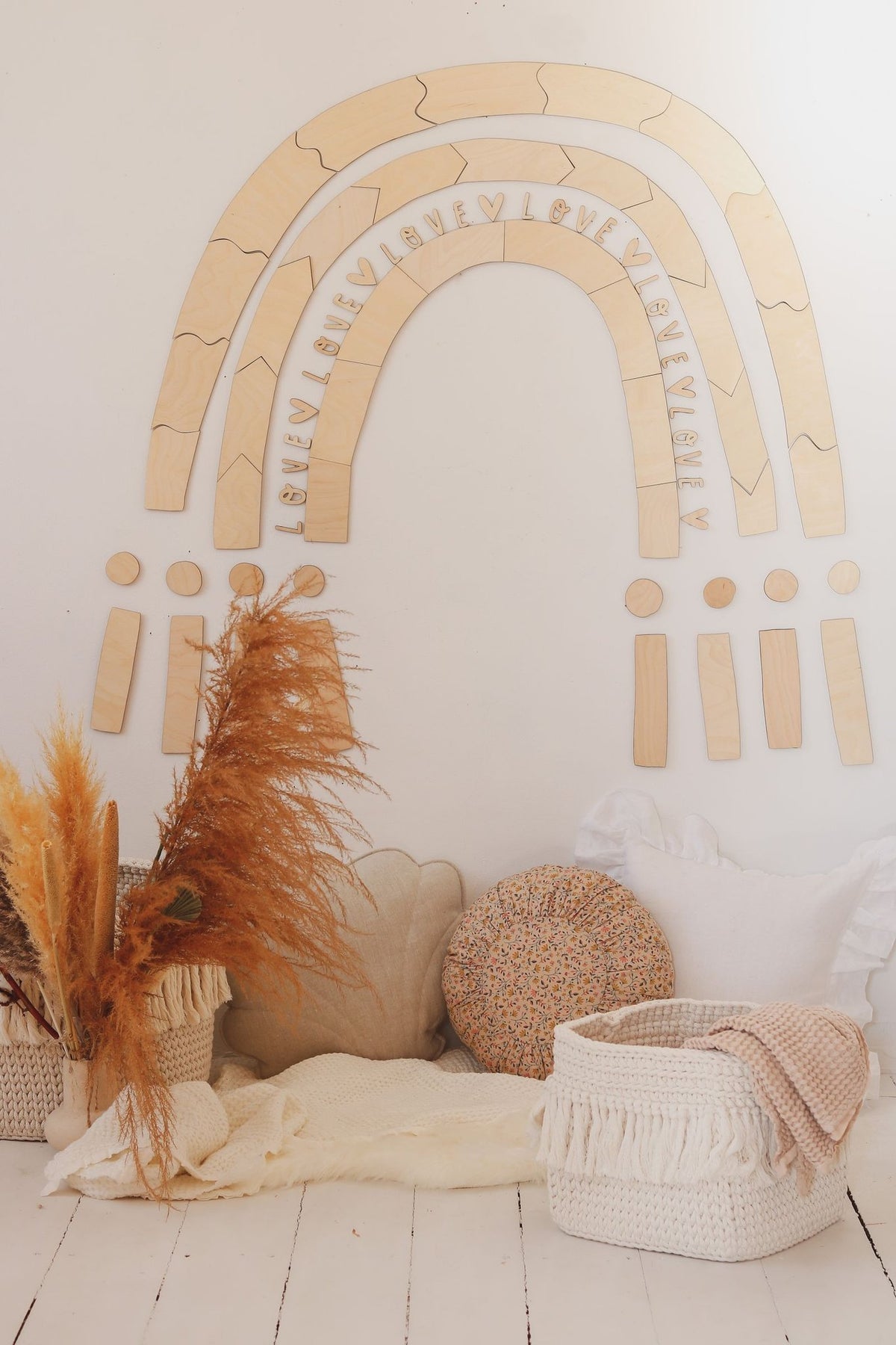 2. Wooden rainbow puzzle wall decoration in a child's room with cushions and decorative baskets, enhancing a warm setting