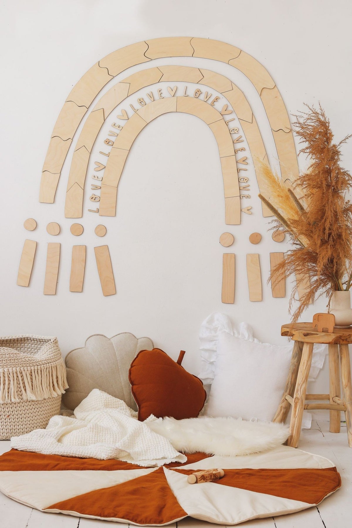 6. Wooden rainbow puzzle wall decoration in a cozy corner with cushions and a small stool, creating a playful environment
