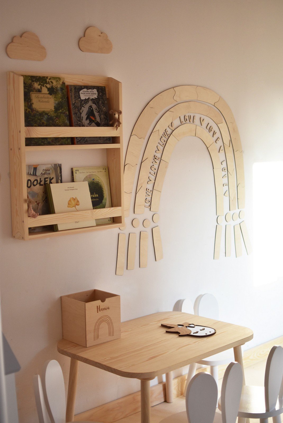 1. Children's room with wooden rainbow puzzle wall decoration above a bookshelf and table, creating a cozy atmosphere