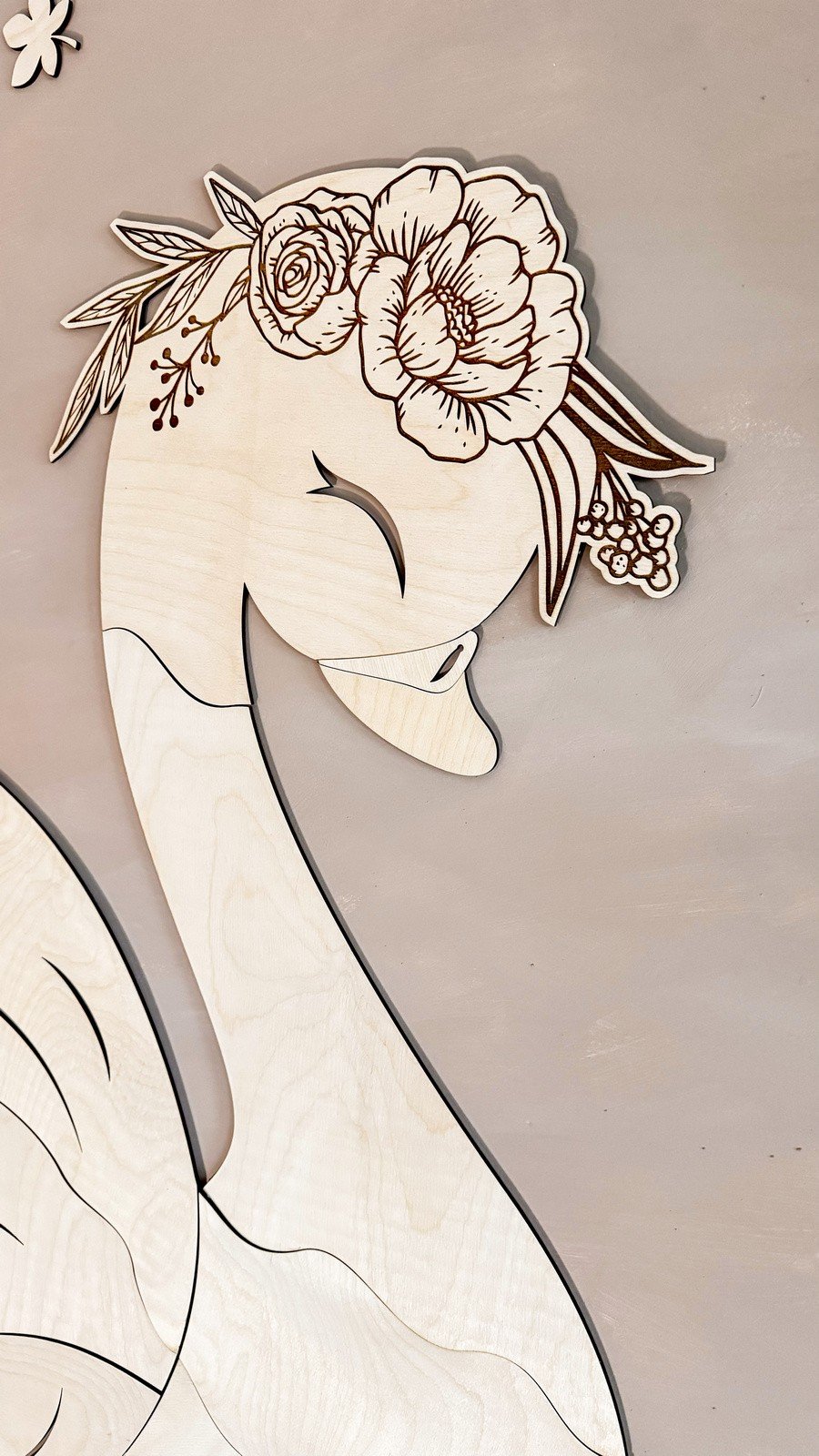 3. Close-up of wooden swan head with embossed flower wreath on birch plywood