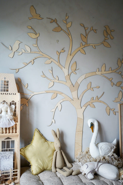 2. Wooden tree wall decoration with birds in a child's room featuring a dollhouse, plush toys, and a swan, enhancing a playful setting.