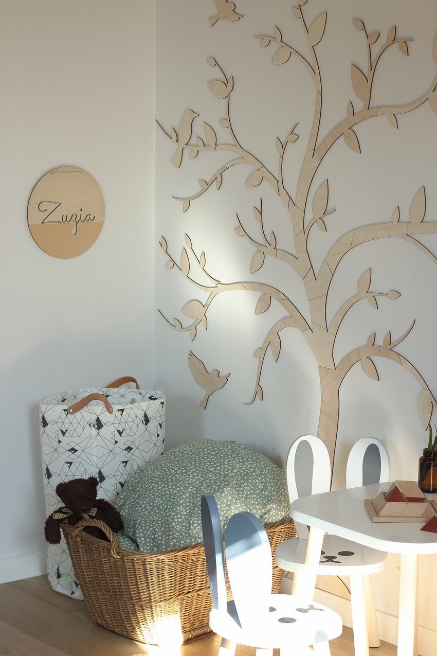 6. Wooden tree wall decoration with birds in a corner with a basket and children's chairs, providing a playful and inviting space.