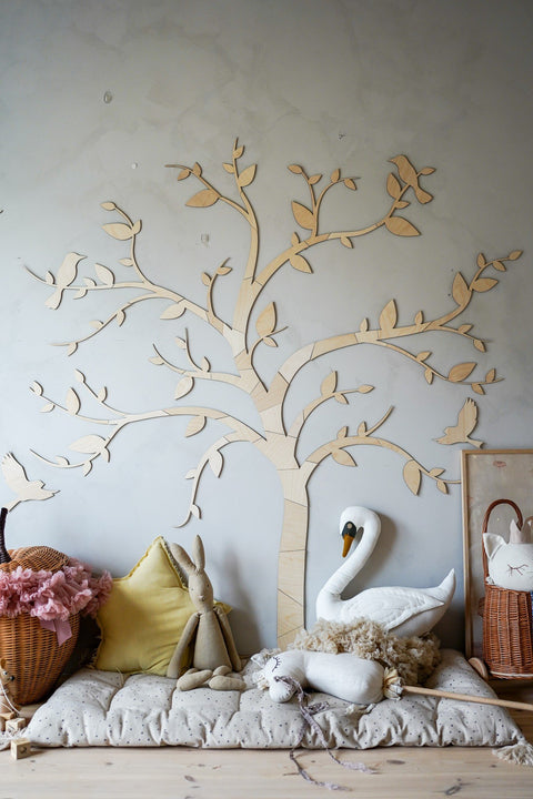 4. Wooden tree wall decoration with birds in a nursery setting with plush toys and a swan, creating a serene and whimsical environment.