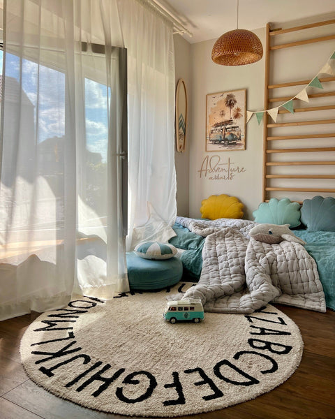 2. Bright child's room with 'Adventure Awaits' wooden sign on wall, round alphabet rug, and toy van on floor