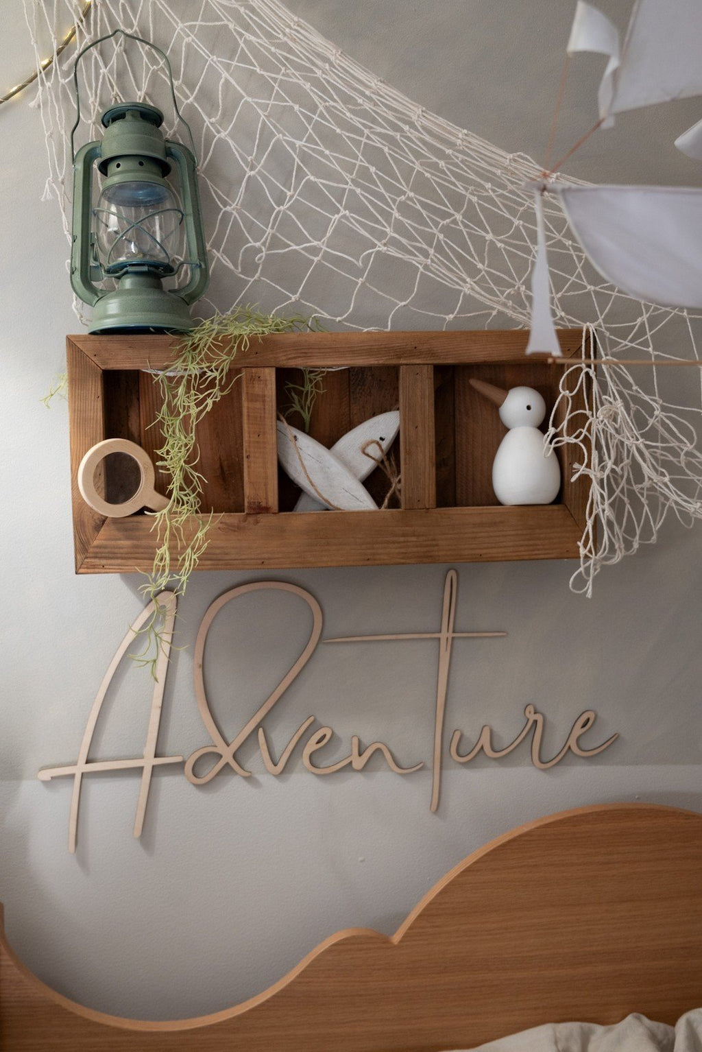 9. Close-up of 'Adventure' part of wooden wall sign with decorative shelf and netting in child's room