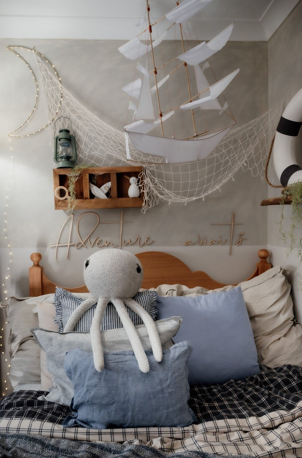 8. Nautical-themed child's room with 'Adventure Awaits' wooden sign, octopus plush, and decorative netting