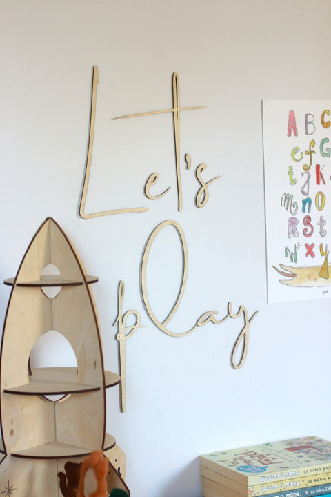 2. Natural plywood 'Let's Play' wall sign in children's room with wooden rocket shelf and colorful alphabet poster