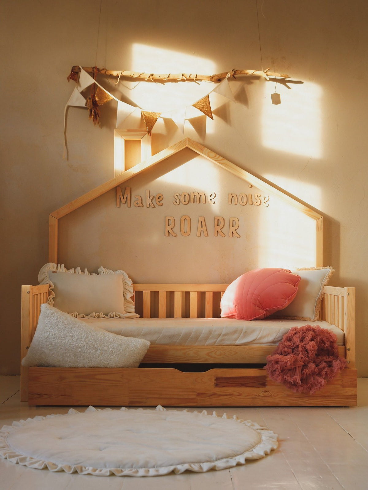 2. Child's room with wooden bed and 'Make some noise ROARR' wall sign, decorated with pillows and bunting