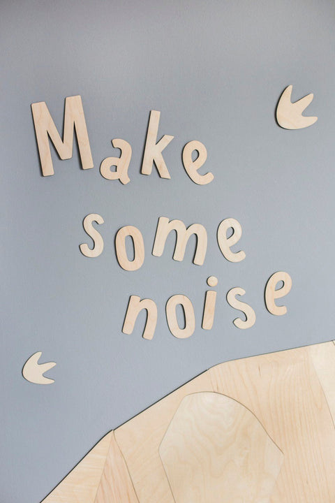 1. Wooden wall sign with 'Make some noise' inscription on grey wall with dinosaur footprints, made from 4mm plywood