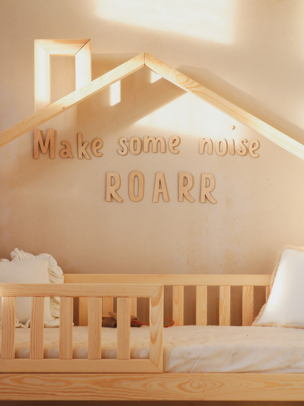 3. Close-up of 'Make some noise ROARR' wooden wall sign above child's bed with natural light