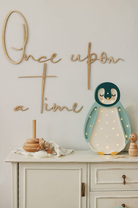 1. Wooden wall sign with 'Once upon a time' inscription above a white cabinet with a penguin night light and toys, creating a whimsical nursery setting
