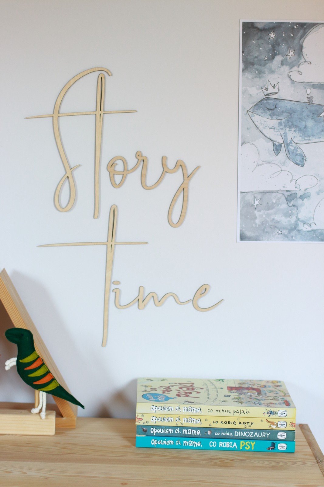 2. Wooden 'Story Time' wall sign above a stack of children's books and a colorful bird figurine, enhancing a playful room setting.