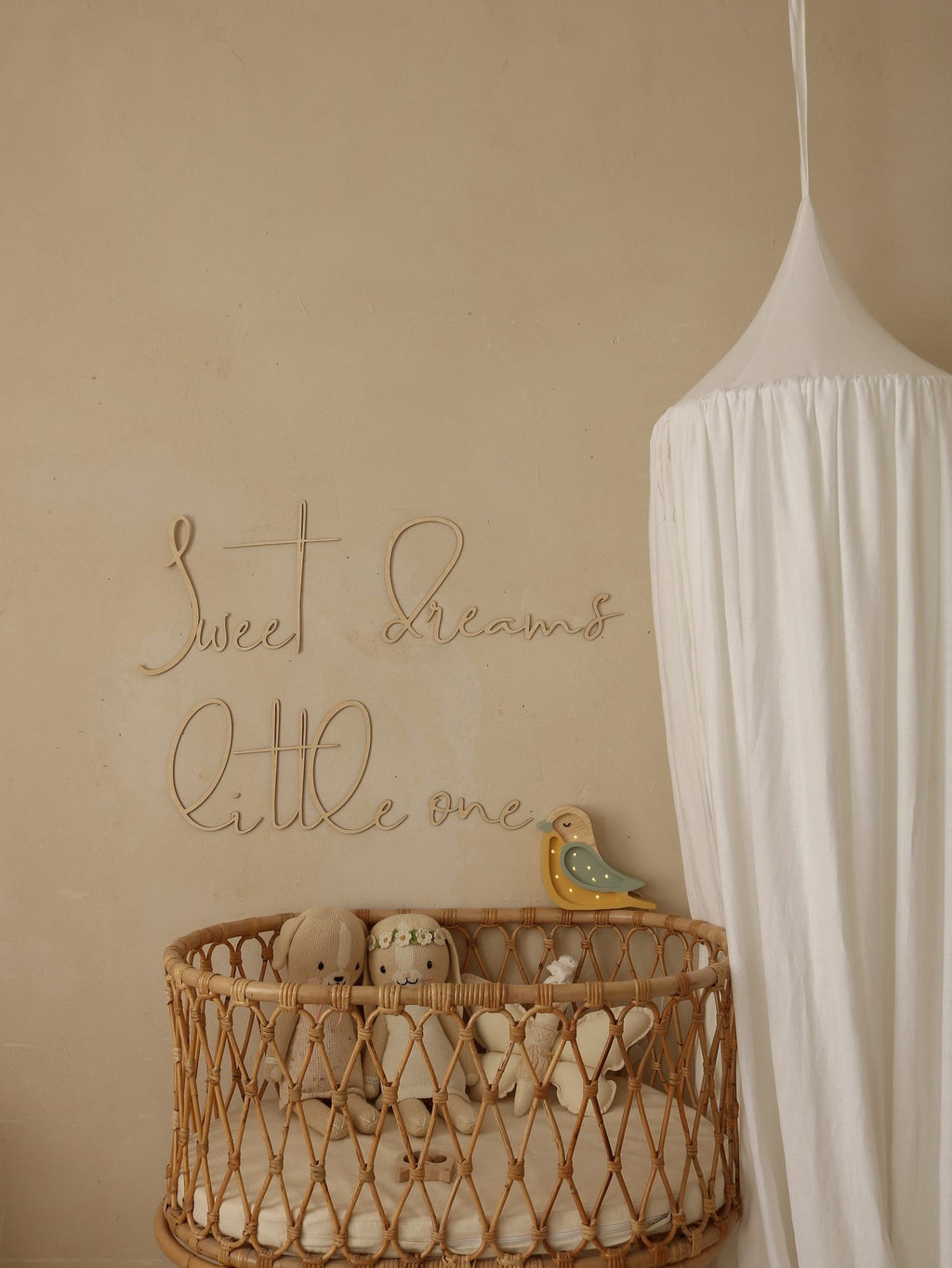 2. Nursery featuring wooden 'Sweet Dreams Little One' sign above wicker crib with plush toys and white canopy