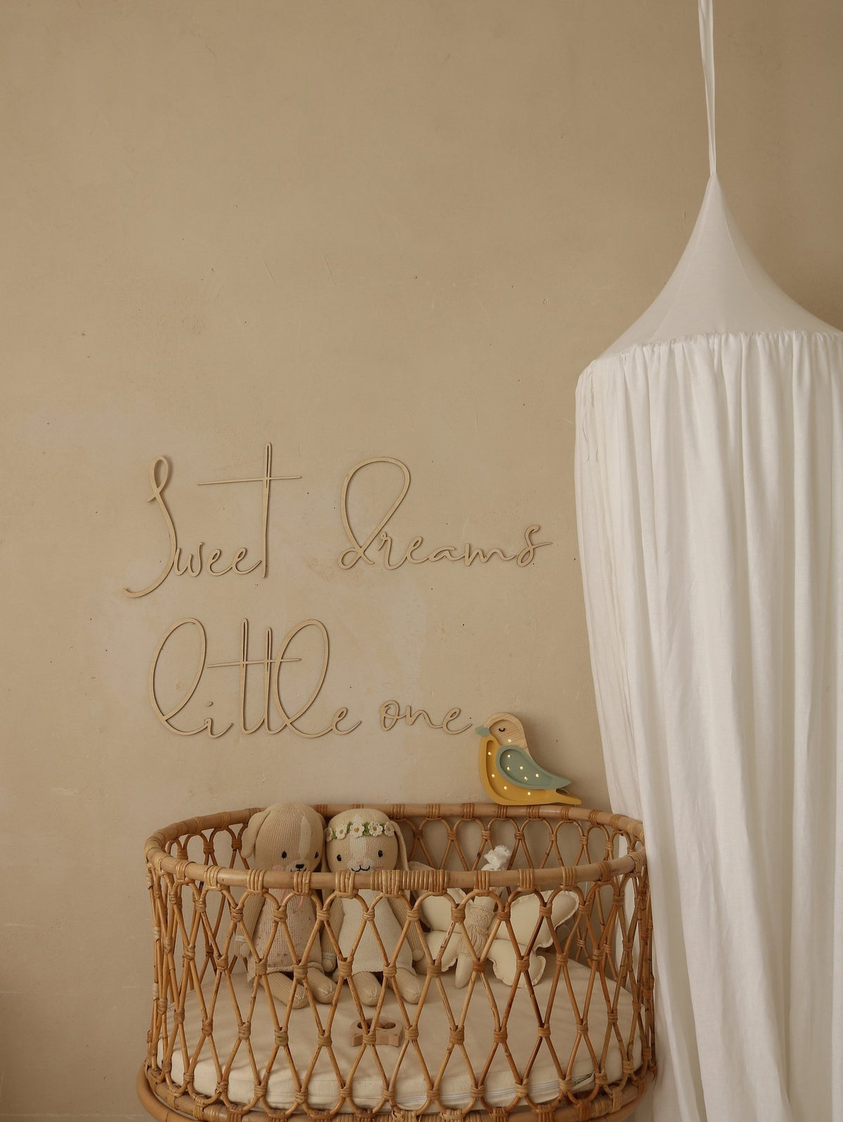 2. Nursery featuring wooden 'Sweet Dreams Little One' sign above wicker crib with plush toys and white canopy