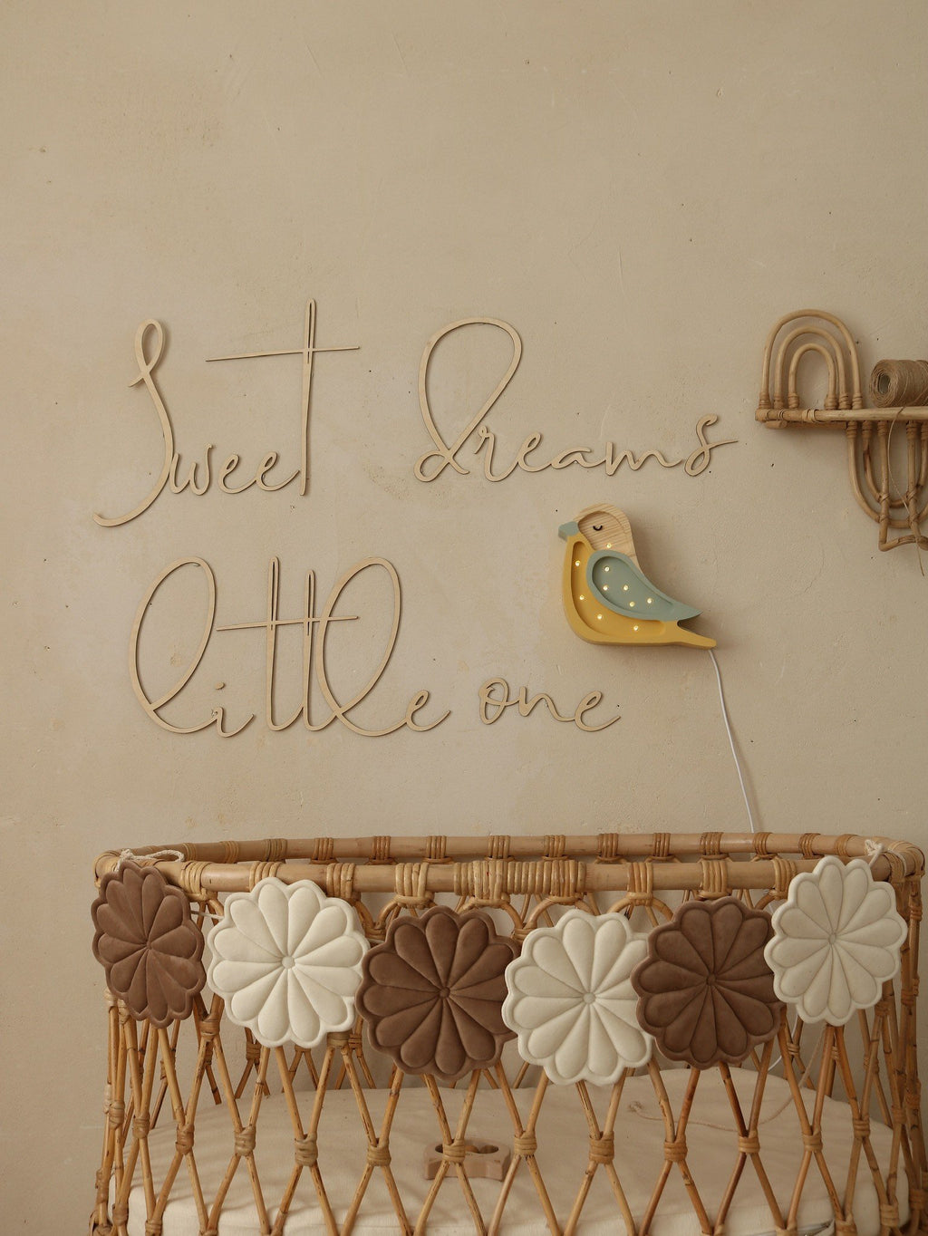 9. Nursery with wooden 'Sweet Dreams Little One' sign above wicker crib with decorative flowers and bird wall light
