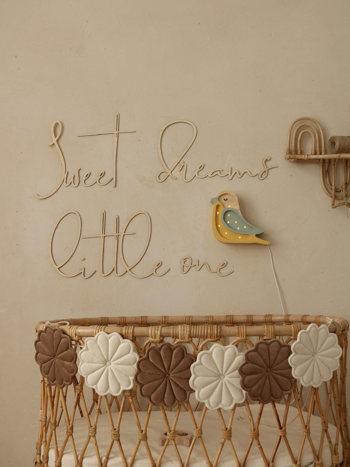 9. Nursery with wooden 'Sweet Dreams Little One' sign above wicker crib with decorative flowers and bird wall light