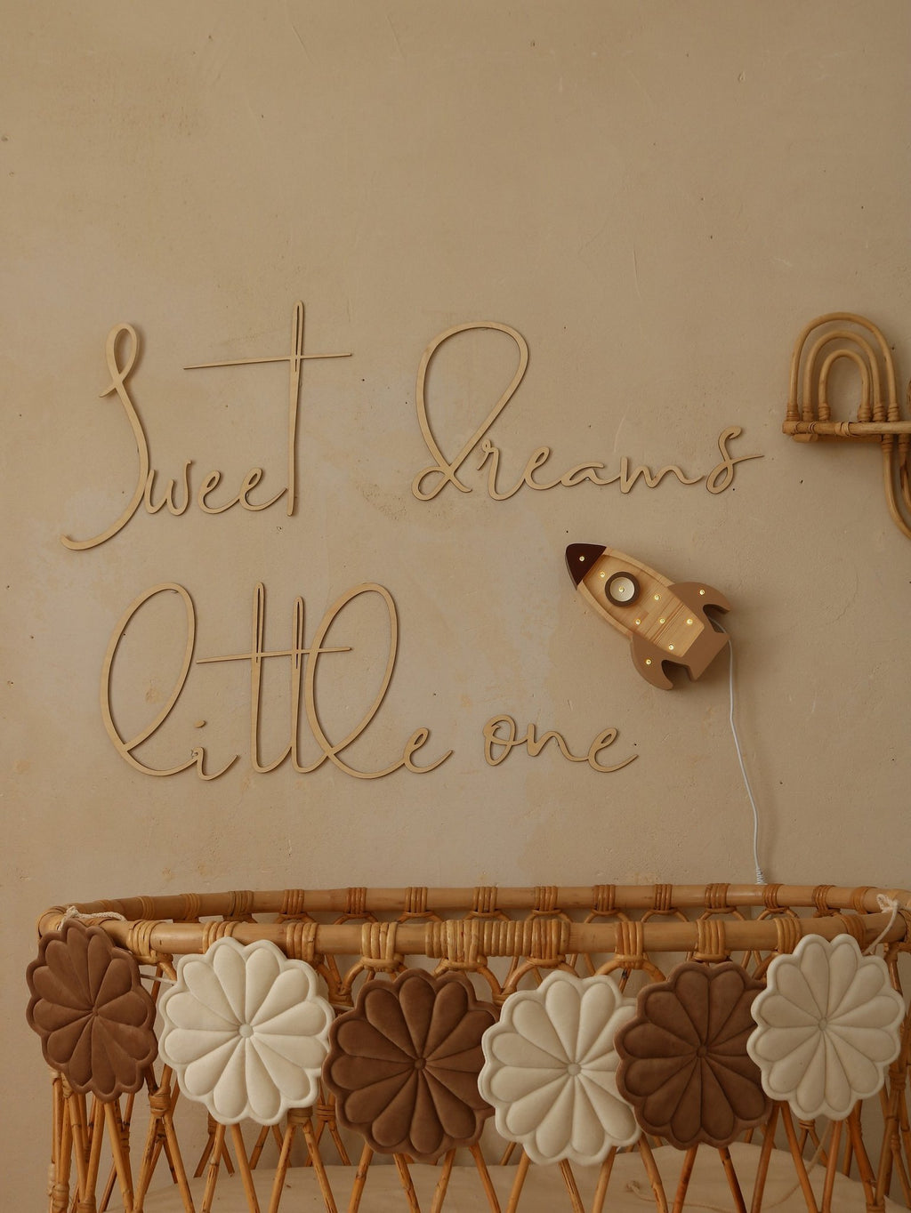 1. Nursery with wooden 'Sweet Dreams Little One' sign above wicker crib with decorative flowers and rocket wall light