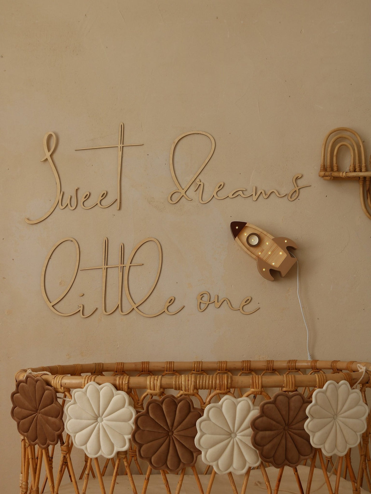 1. Nursery with wooden 'Sweet Dreams Little One' sign above wicker crib with decorative flowers and rocket wall light
