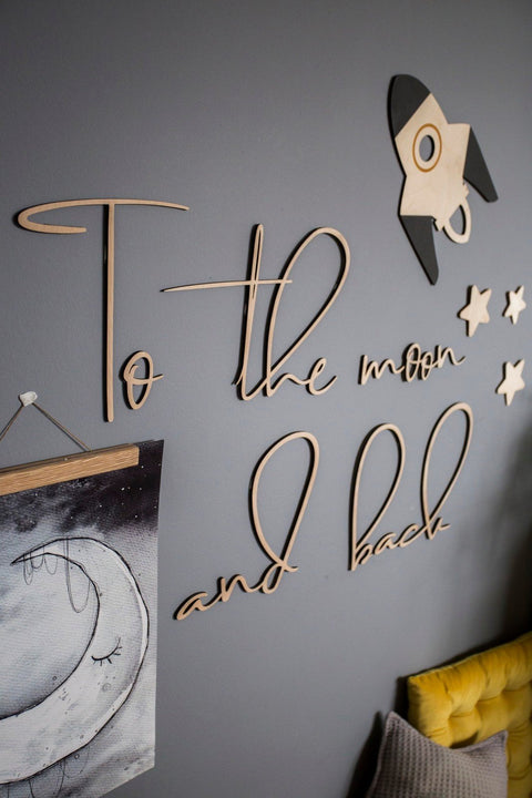 1. Wooden wall sign with 'To the moon and back' inscription on grey wall, accompanied by a rocket and stars, creating a whimsical decor for a child's room.