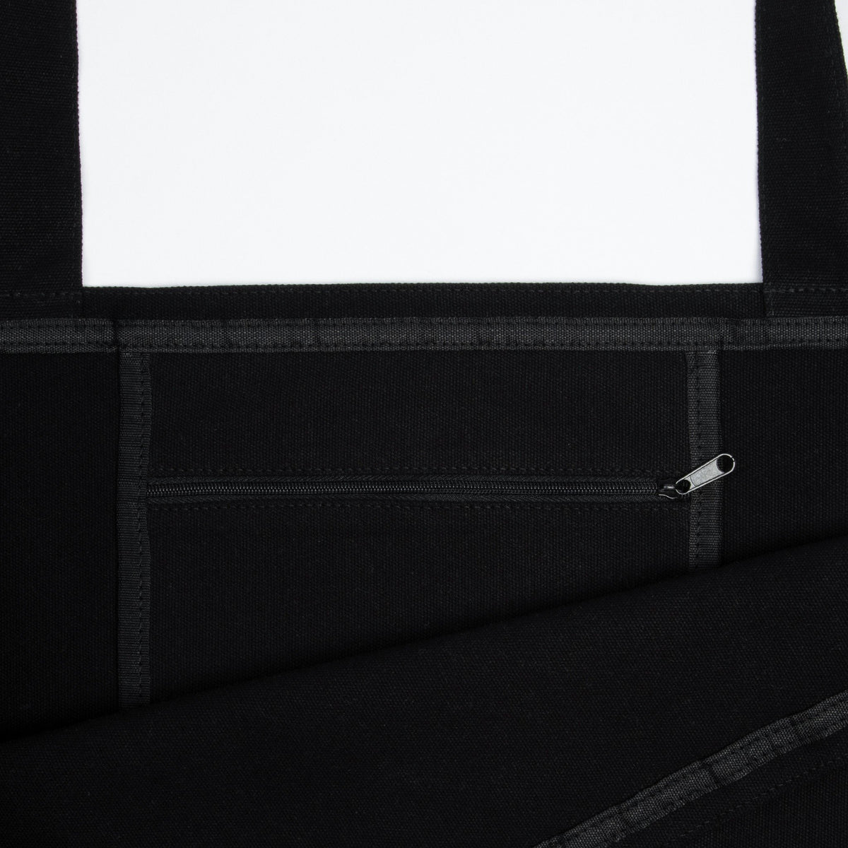 4. Close-up of black XXL Novels Tote Bag interior, showing zipper pocket and heavy cotton material