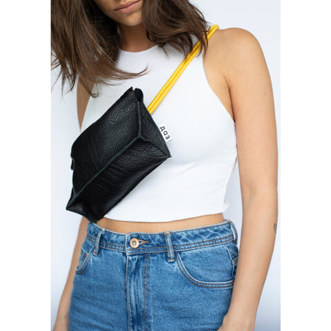 1. Women's handmade leather bum bag in black with yellow strap worn crossbody, featuring Daz Studio logo, styled with white top and denim jeans