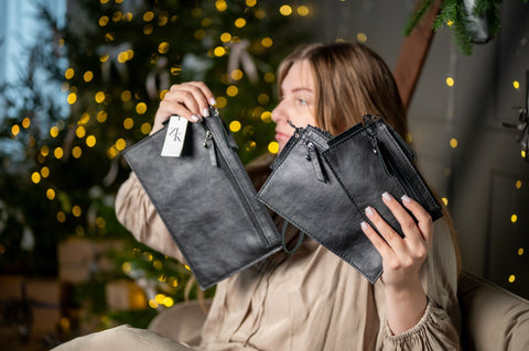 2. Woman displaying two sizes of Zelma Kraft black wristlet wallets, highlighting versatility and design