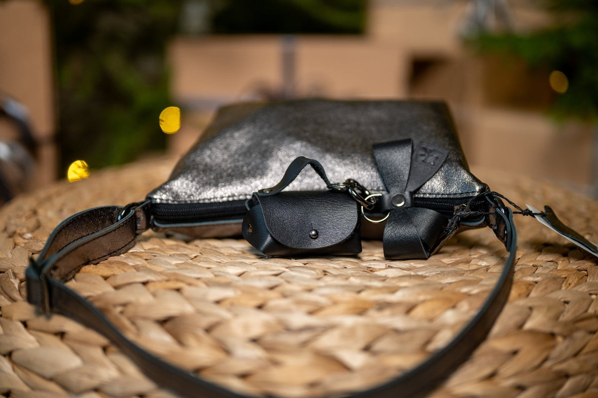 16. Zelma Kraft mini leather charm with bow attached to black leather bag, highlighting versatility