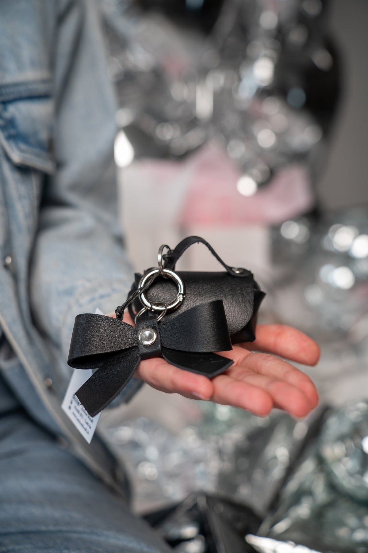 15. Zelma Kraft mini leather charm set with bow and hook, held in hand, showcasing silver metal details