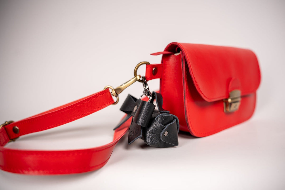 8. Zelma Kraft mini leather charm with bow attached to red leather bag, highlighting versatility