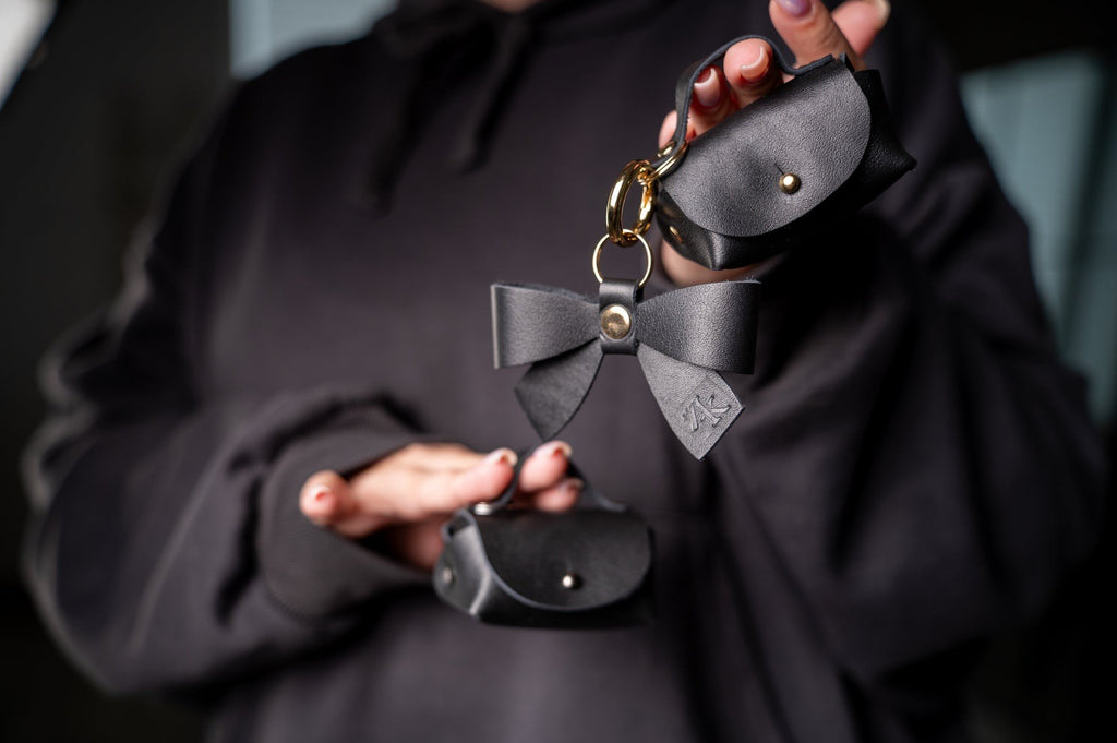 2. Zelma Kraft mini leather charm set with bow and hook, displayed in hand, featuring gold metal details