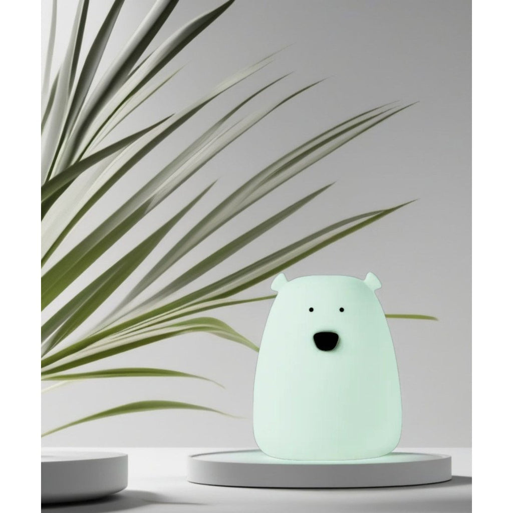3. Arctic green mini bear light on a white platform with green plant leaves in the background