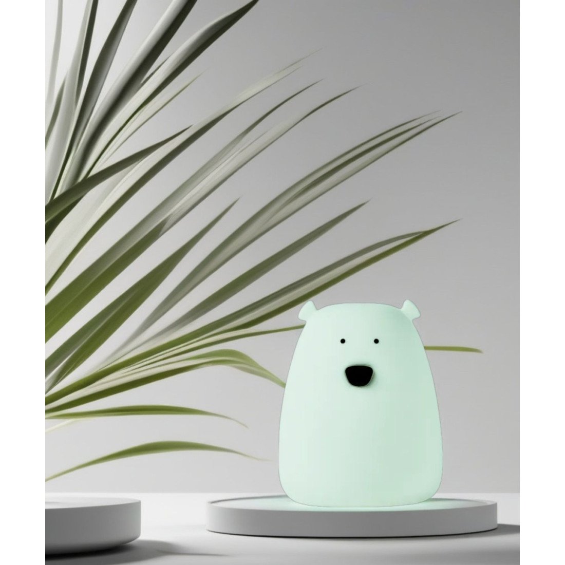 3. Arctic green mini bear light on a white platform with green plant leaves in the background