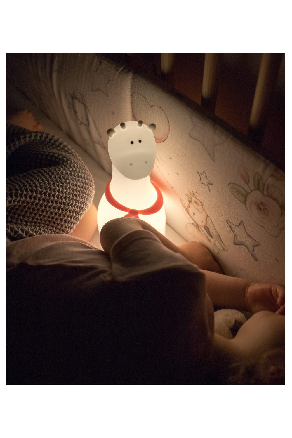 1. Child sleeping with glowing white silicone giraffe lamp with red scarf in crib