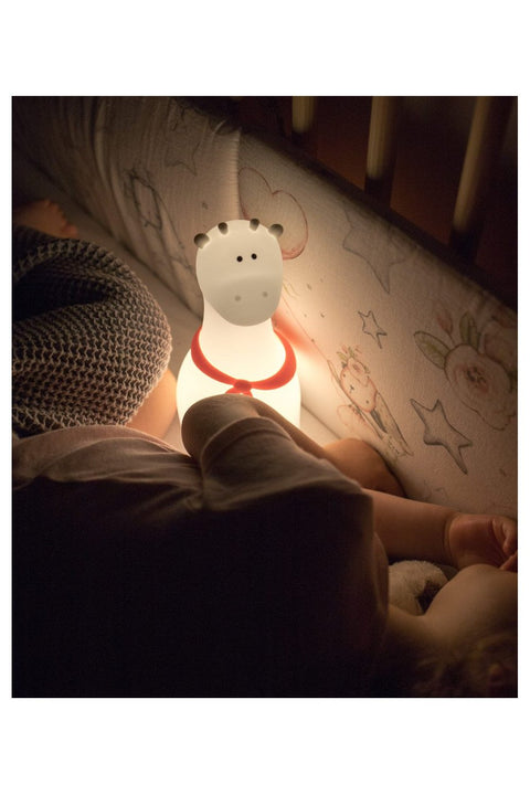 1. Child sleeping with glowing white silicone giraffe lamp with red scarf in crib