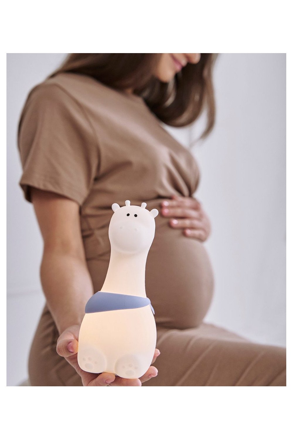 1. Pregnant woman holding glowing white silicone giraffe lamp with blue scarf